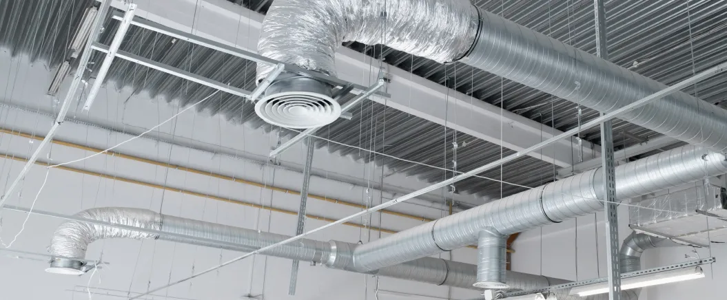 Industrial HVAC ventilation system with exposed metal air ducts and vents installed on a commercial building ceiling.