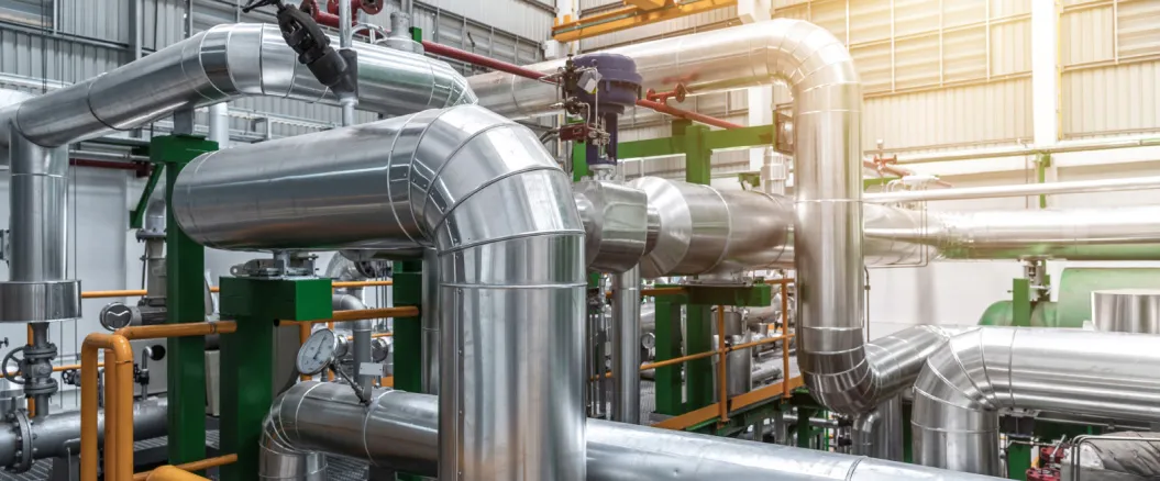 Industrial facility with large, shiny metal pipes and valves as part of a complex HVAC or manufacturing system.
