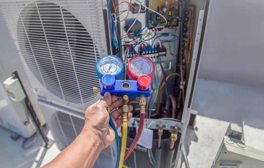 Technician using a manifold gauge to measure pressure levels on an outdoor air conditioning unit during maintenance. 