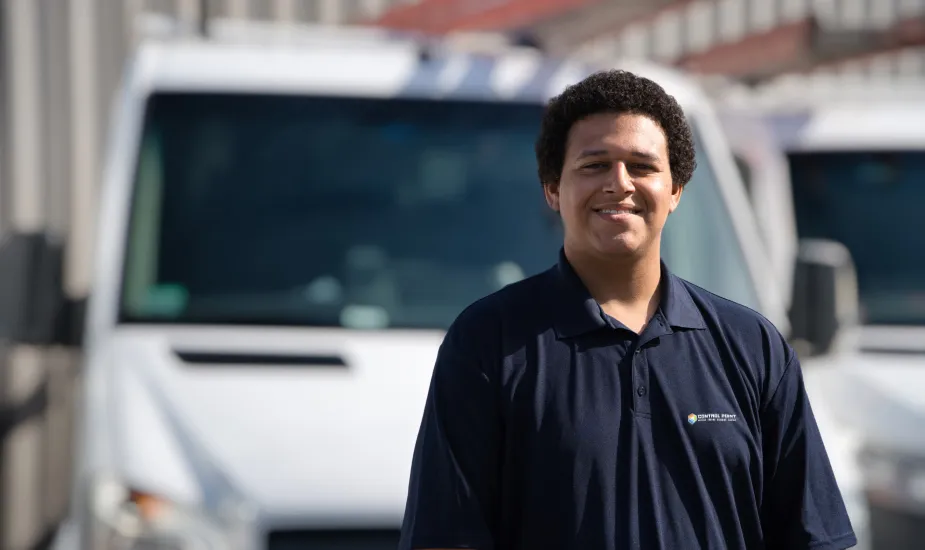 Technician standing and smiling in front of a service van.